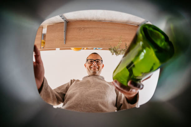 istock Young Man Putting Glass Bottle In The Recycling Bin 1400088334