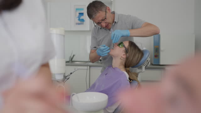 Caucasian male dentist descaling female patient dental plaque
