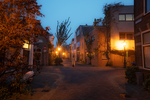 Young Caucasian woman in coat  walking in Leiden town at night