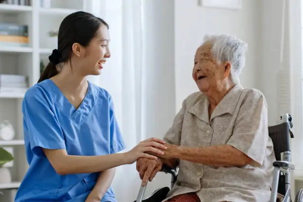 Photo of Young Asian woman, nurse, caregiver, carer of nursing home talking with senior Asian woman feeling happy at home