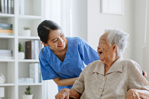 Joven asiática, enfermera, cuidadora, cuidadora de un hogar de ancianos hablando con una mujer asiática mayor que se siente feliz en casa photo