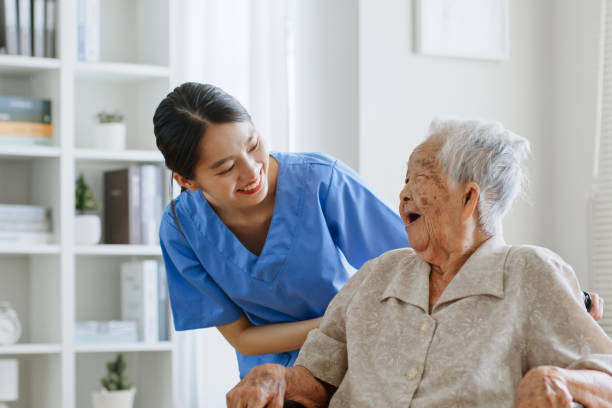 Young Asian woman, nurse, caregiver, carer of nursing home talking with senior Asian woman feeling happy at home stock photo