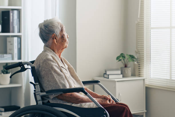 anciana asiática anciana solitaria, sentada sola en la habitación, mirando por la ventana - pensive senior adult looking through window indoors fotografías e imágenes de stock