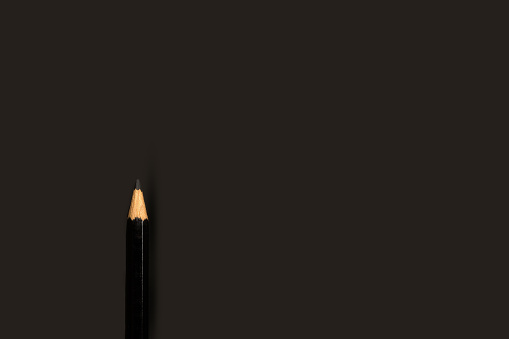 Black pencil on a black background with copy space