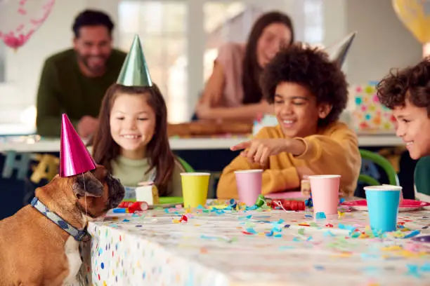 Photo of Pet Dog At Table As Girl With Parents And Friends Celebrate Birthday Party At Home