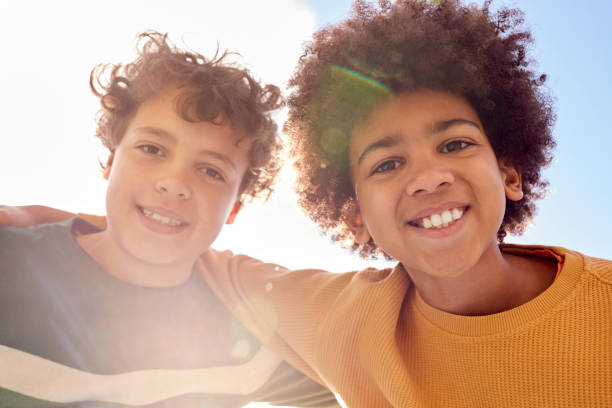istock Low Angle Portrait Of Two Boys Having Fun Playing Outdoors Looking Down Into Camera With Lens Flare 1400092843