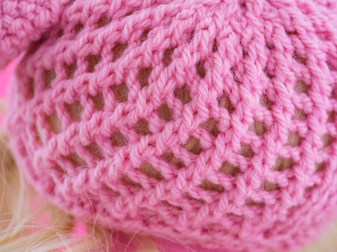 A close-up shot of a knitted pink hat on a doll head