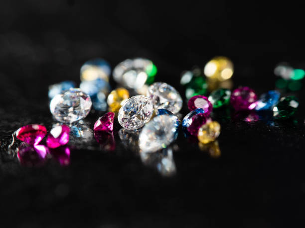 ブラックの背景にグループマルチカラーダイヤモンドのクローズアップショット - jewelry gem gold reflection ストックフォトと画像