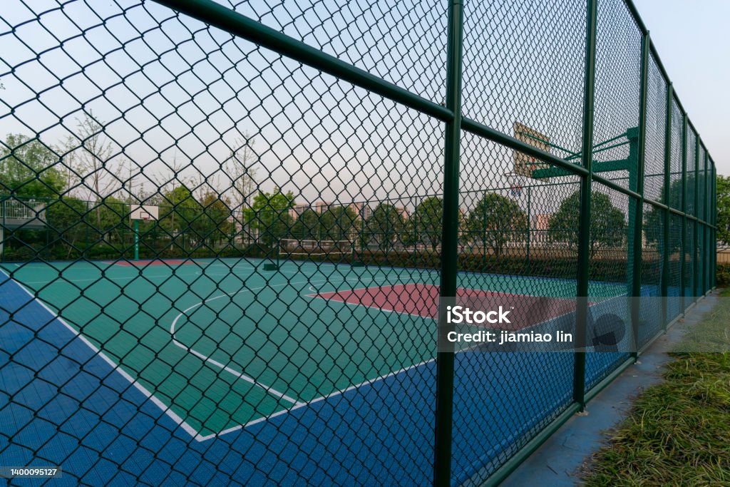 basketball court behind barbed wire Fence Stock Photo