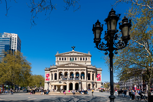 Frankfurt, Germany - April, 20. 2022: Old opera house in Frankfurt in Germany. Some pedestrians are around.