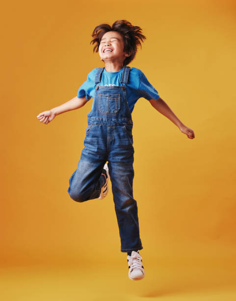 One cute mixed race child wearing casual clothes while having fun and being energetic against an orange copyspace background. Asian kid being active One cute mixed race child wearing casual clothes while having fun and being energetic against an orange copyspace background. Asian kid being active one little boy stock pictures, royalty-free photos & images