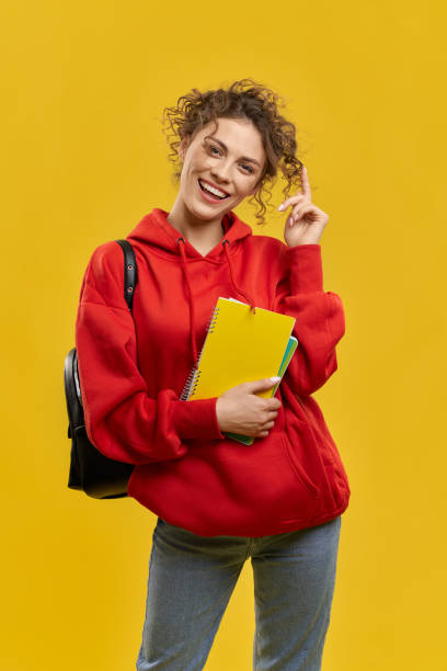 Pretty student with curly hair standing, smiling. stock photo
