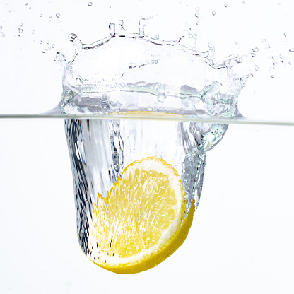 lemon slice falls into the water on a white background