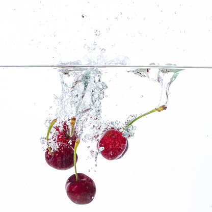 cherries fall into the water in the water on a white background