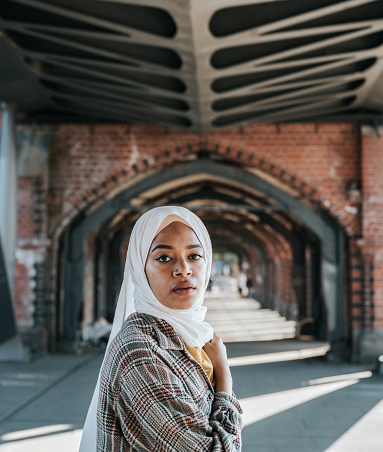 portrait of young woman with hijab on Oberbaumbrücke in Berlin at sunny late summer day