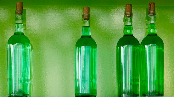 Four bottles side by side in green with green background