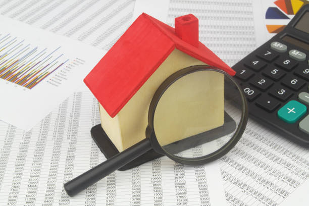 House model with magnifying glass and calculator on financial documents. stock photo