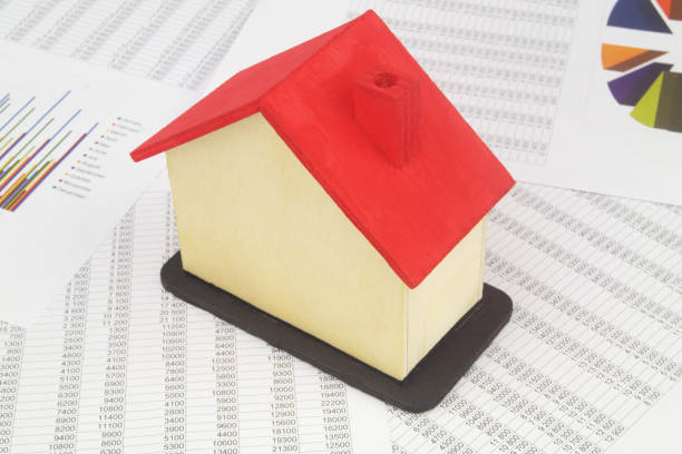 istock Wooden house with red roof on documents with financial data. 1400101304