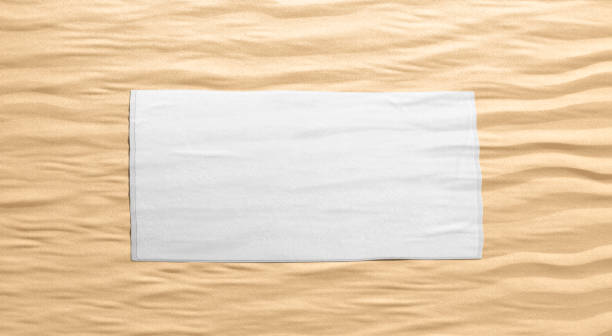 istock Blank white smooth unfolded big towel mockup, sand background 1400104545