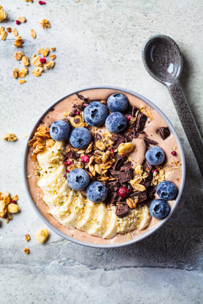 czekoladowa miska koktajlu bananowego z muesli, jagodami i nasionami konopi, szare tło. zdrowa wegańska koncepcja przepisu. - hemp seed nut raw zdjęcia i obrazy z banku zdjęć