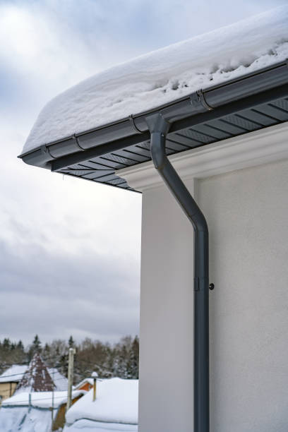 istock Metal Downpipe system, Guttering System, External downpipes and drainage pipes under snow. Corner of house with roof made of gray metal tiles and gutter covered with thick layer of snow in winter. 1400106157
