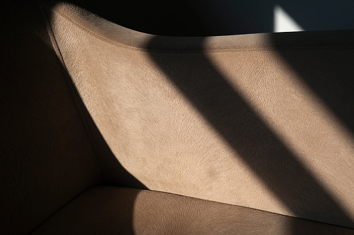 Shadowy abstract fabric detail of an armchair. Horizontal beige fabric or textile detail as background.