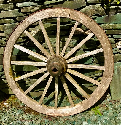 Antique vintage wooden carriage wheel hanging on the wall. Home rustic decorations.