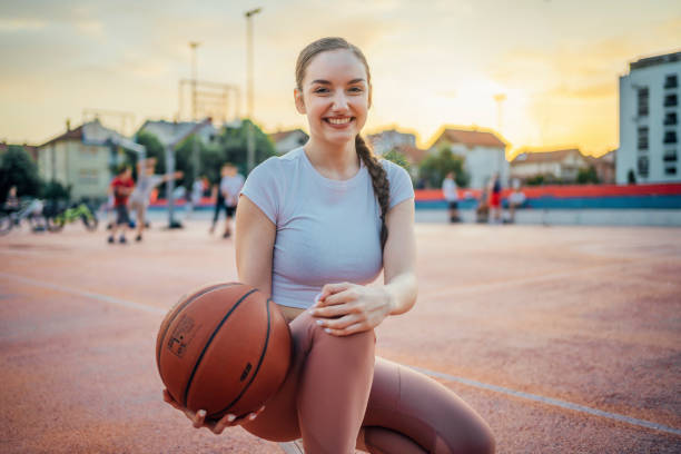 Young smiling woman with a basketball in an outdoor court