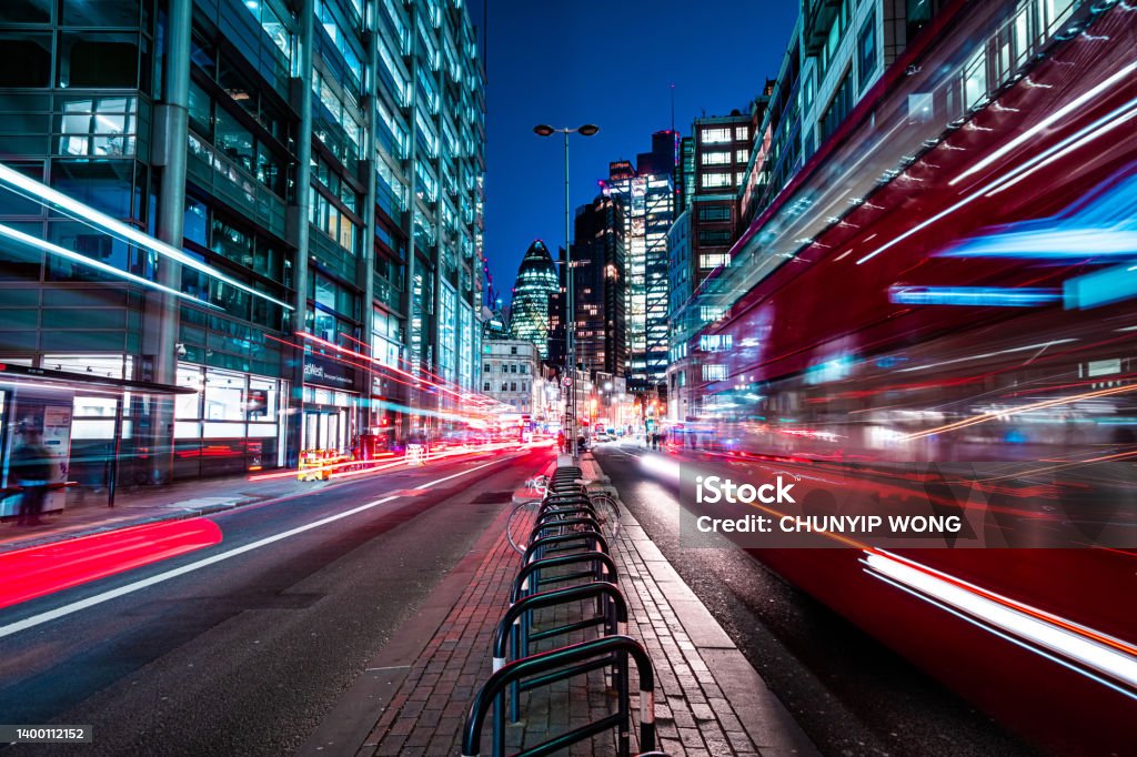 London red buses zooming through City skyscrapers night street City Stock Photo