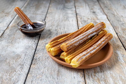 traditional Spanish pastries - Churros and chocolate sauce on a wooden background