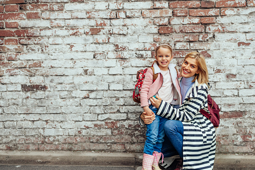 Love of mother and daughter. Happy women standing in front of brick wall in the city with her beloved daughter