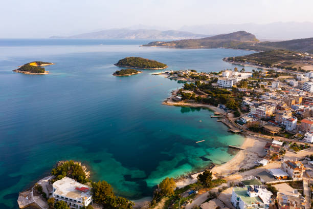 Drone view of Albanian resort of Ksamil on coast of Ionian sea Picturesque drone view of famous Albanian resort of Ksamil on coast of Ionian sea with sandy beaches and turquoise water on sunny spring day albania stock pictures, royalty-free photos & images