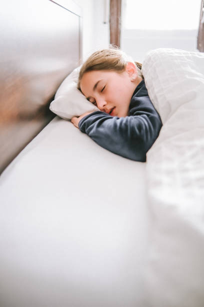 istock Girl sleeping in a bed with white quilt 1400116692