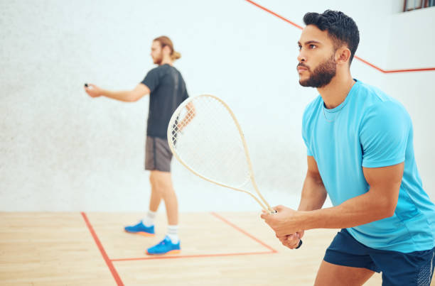 istock Young athletic squash player getting ready for playing opponent in competitive court game. Fit active mixed race athlete looking focused during training challenge in sports centre. Waiting for serve 1400118192