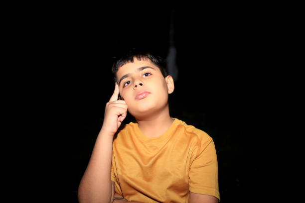 Elementary age child of Indian ethnicity standing portrait at night thinking something.