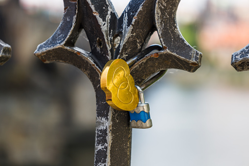 Closeup view of love padlocks hanging on a bridge fence.