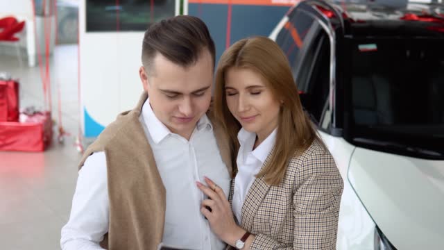 Male dealer passing car documents to happy couple. Auto business, car sale, technology and people concept