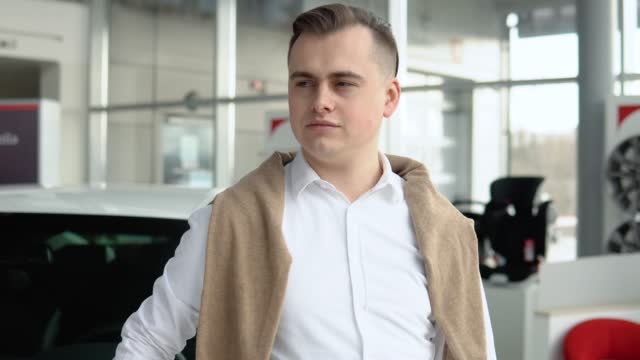 Elegant stylish man showing keys of his new car in dealership