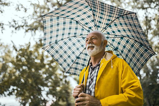 Adult Asian man smiling to camera while holding an umbrella
