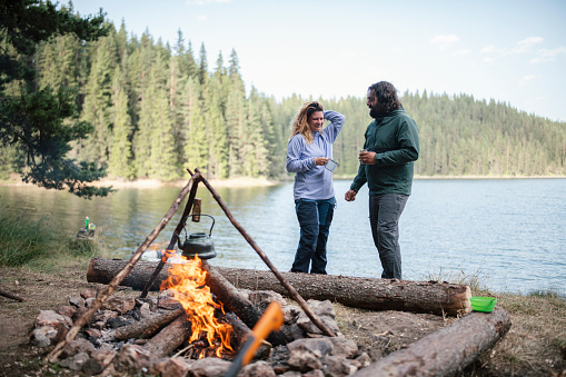 Young couple in love standing next to campfire and talking.