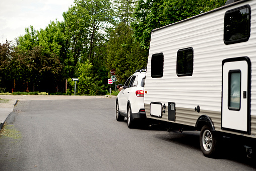 Car with RV on the street leaving for summer vacations. Horizontal full length outdoors shot with copy space.