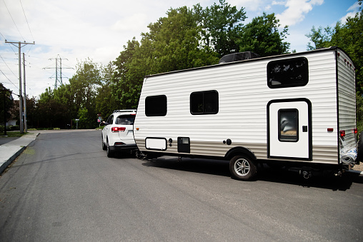 Car with RV on the street leaving for summer vacations. Horizontal full length outdoors shot with copy space.