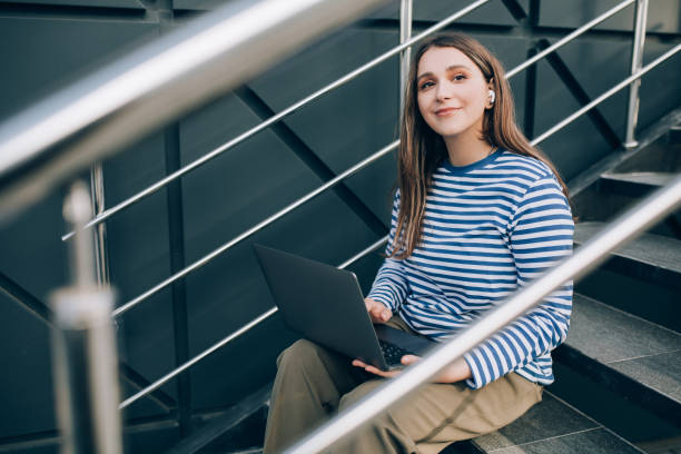 istock Young woman freelancer working online using her laptop, sitting on stairs. 1400131737