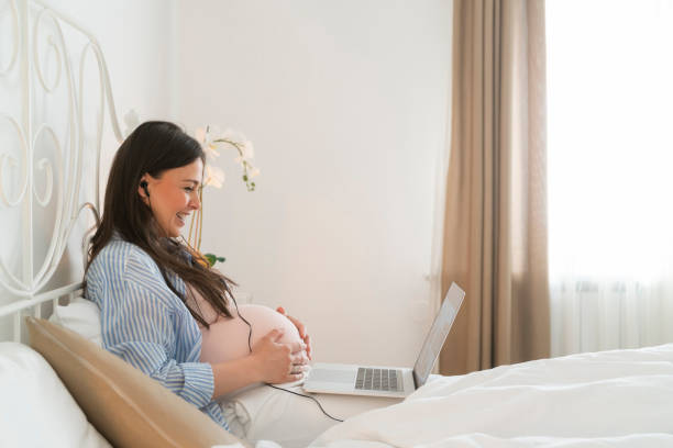 беременная женщина, используя ноутбук в постели - 7677 стоковые фото и изображения