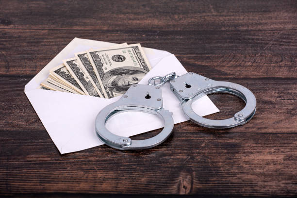 istock handcuffs lying on an open white envelope with dollars, close-up on a dark background 1400132684
