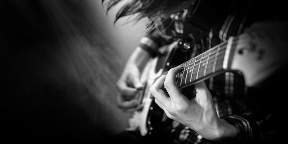 Electric guitar playing. Young men playing electric guitar. Black and white closeup Photography.