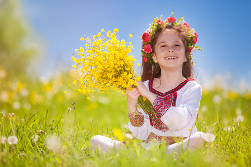 Studio portrait of beautiful little girl holding big colorful bouquet of various flowers.