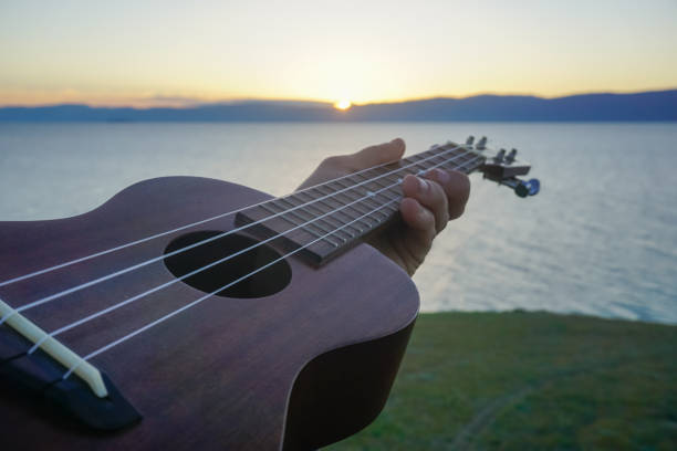 istock Ukulele in the hand of a man at sunset 1400140262