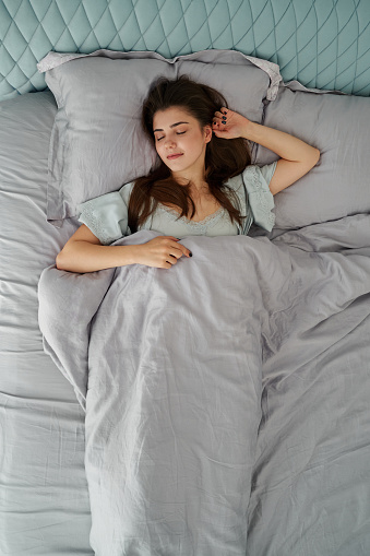 Beautiful woman sleeping in comfort bed. Rest, bed linen. Apartment. Home lifestyle