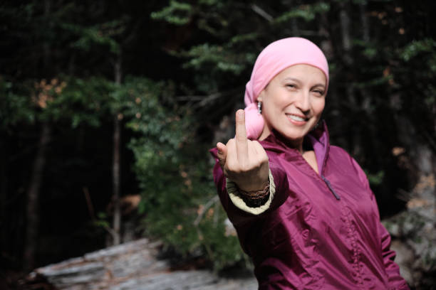 Woman cancer survivor makes a gesture with her hand while looking at the camera and smiling.